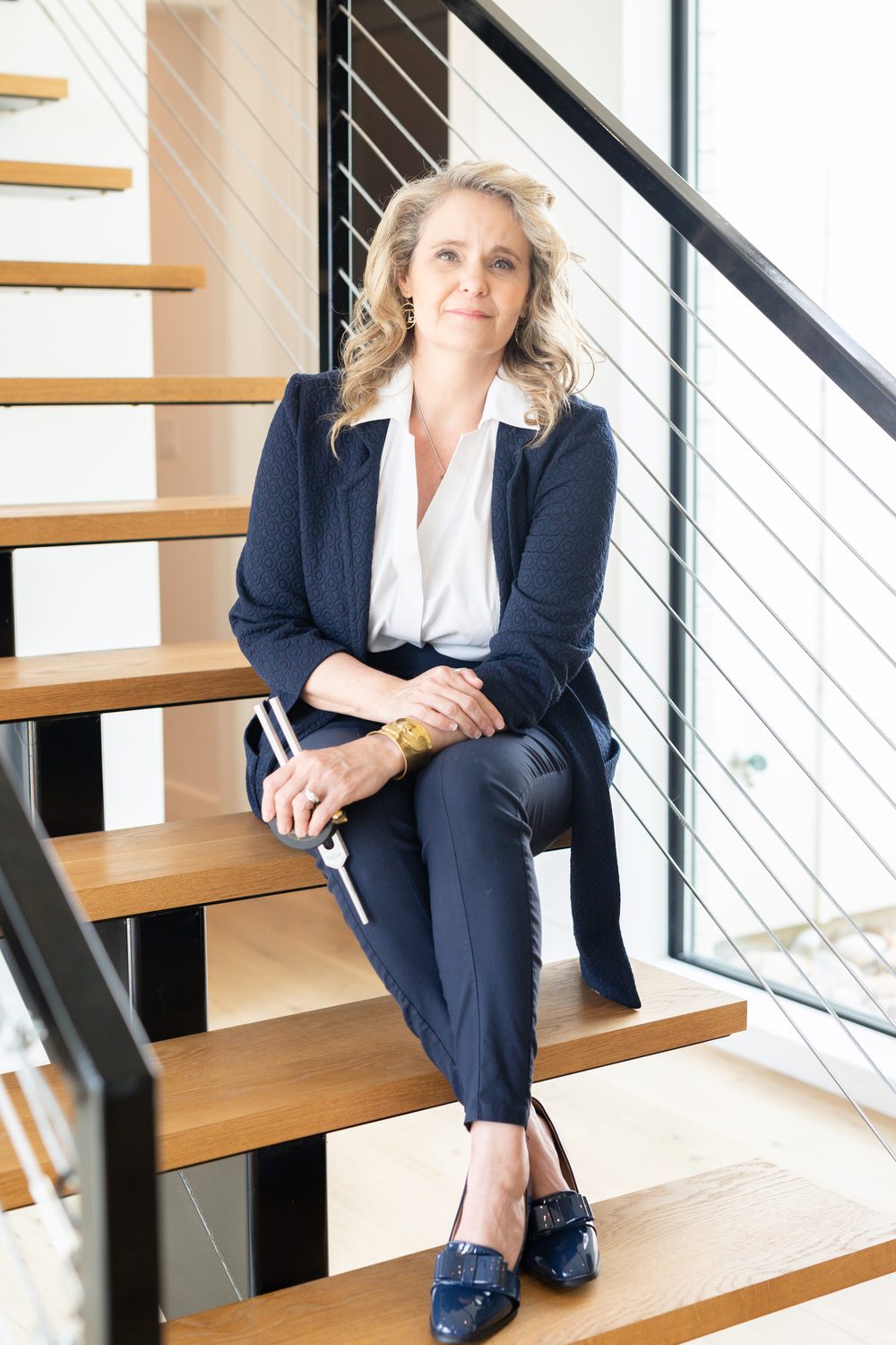 Dr. Amy on a staircase holding a tuning fork